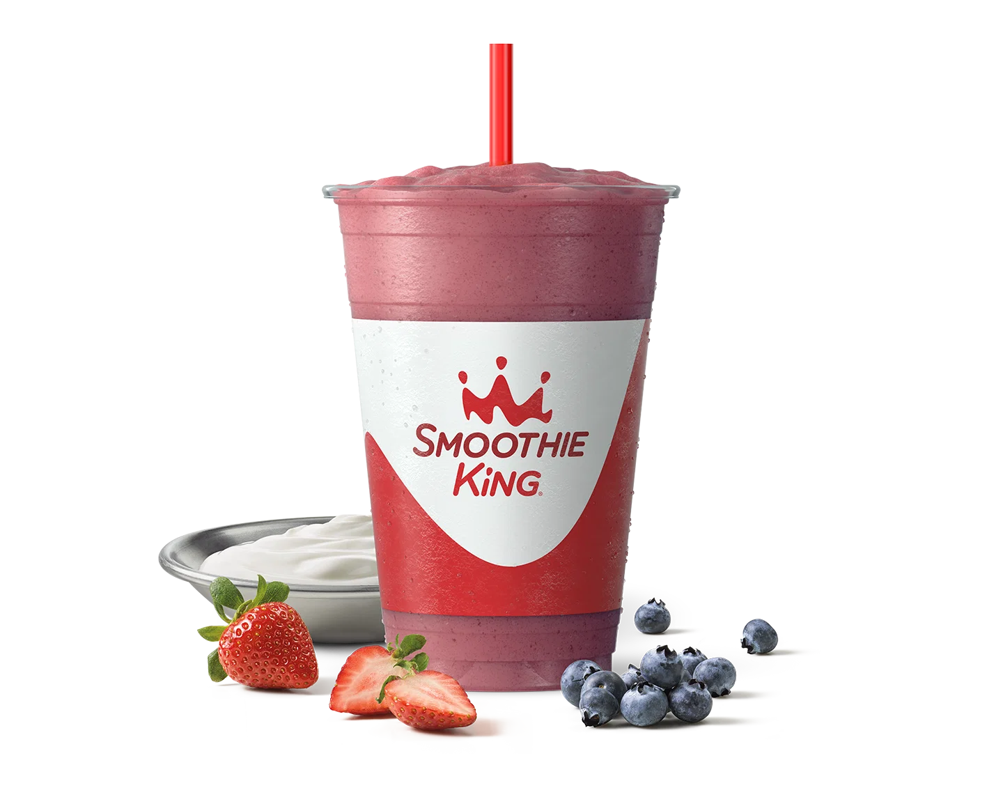 A healthy smoothie with blueberries and strawberries sitting beside it