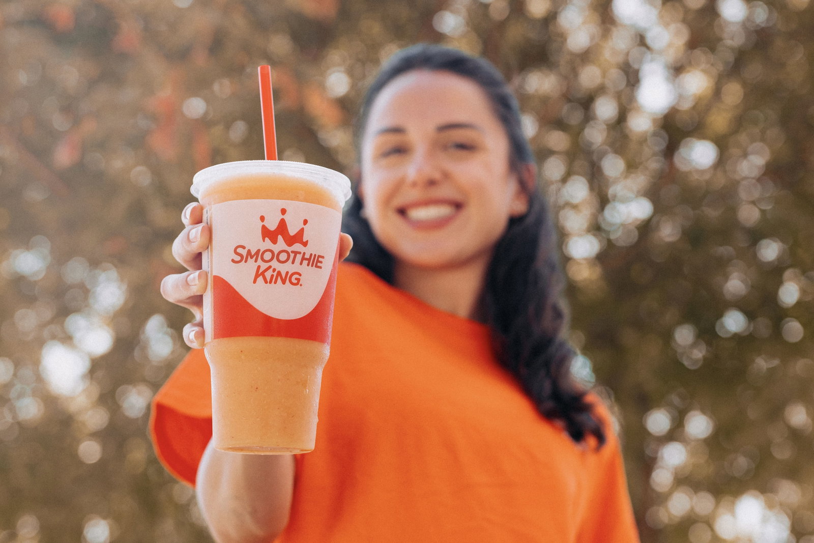 A young woman holding a pumpkin smoothie from Smoothie King